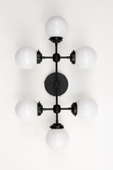 Large vanity light sconce or ceiling flushmount with 6 light bulbs.  Large, oversized wall sconce for a large bathroom or for a low 8 or 9 foot ceiling room that needs lots of light.  Modern shape with six white globes.  Great light fixture for a bathroom that does not have any natural light. Makes a small to medium bathroom bright enough to apply makeup.  Large vanity light in black, brass, or chrome.    Black and white large vanity light