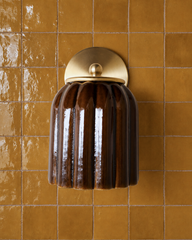 Deep mustard tile with the glossy, hand-glazed look of zellige sets a warm, saturated tone for this bathroom wall, and the Marcella Sconce in Chicory Brown leans right into it rather than fighting the color. Both the tile and the fluted shade catch light in a similar handmade way, making the pairing feel intentional. A confident choice for warm bathroom tile ideas and anyone drawn to mustard and brown together.