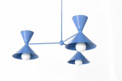 Soft periwinkle is the blue that makes a room feel calm, sunny, and a little coastal, and this Clancy chandelier commits all the way, shades, arms, and stem in one glossy celestial blue. Three double-cone bowtie shades radiate from a central sphere hub in a crisp Italian-inspired mid-century silhouette, throwing light up and down from each arm. It's built to anchor a dining table, kitchen island, or entry, the kind of statement piece that makes people ask whose house this is. Fresh, sculptural, and cheerful