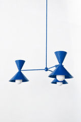 A saturated cobalt is the fastest way to give a room real personality, and this monochromatic Clancy chandelier goes all in, shades, arms, and stem in one glossy Mediterranean blue. Three double-cone bowtie shades fan out from a central sphere hub in a crisp Italian-inspired mid-century silhouette, casting light up and down from every arm. It's made to headline a dining table, kitchen island, or entry, the kind of piece that anchors the whole room and starts conversations. Graphic against white, brass, and 