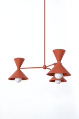 Terra cotta is the warm clay tone that makes a room feel earthy, grounded, and a little sun-baked, and this mid-century modern Clancy chandelier commits all the way, shades, arms, and stem in one soft matte terra cotta. Three double-cone bowtie shades radiate from a central sphere hub in a fun, sculptural MCM silhouette, throwing light up and down from each arm. The flat finish keeps it natural and understated, the kind of statement piece that anchors a dining table, kitchen island, or entry without any shi