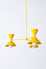 Bright yellow is the color that instantly makes a room feel happy, sunny, and full of energy, and this mid-century modern Clancy chandelier commits all the way, shades, arms, and stem in one glossy yellow. Three double-cone bowtie shades radiate from a central sphere hub in a fun, sculptural MCM silhouette, throwing light up and down from each arm. It's built to be the star over a dining table, a kitchen island, a breakfast nook, or a cheerful entry, the kind of playful statement piece that makes people ask