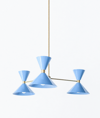 Soft periwinkle and warm brass is the pairing that makes a room feel calm, sunny, and a little coastal, and this mid-century modern Clancy chandelier brings them together beautifully. Three glossy celestial blue double-cone shades radiate from a brass central hub on slim brass arms, in a fun, sculptural MCM silhouette that throws light up and down from each arm. The brass stem and collars warm up the soft blue and give the whole piece a polished, collected feel. It's built to be the star over a dining table