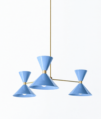 A soft hydrangea-blue chandelier that brings vintage Italian modern character and a hit of color to a dining room, bedroom, or entryway. The Clancy Chandelier pairs three splayed brass arms with glossy periwinkle hourglass double-cone shades, each set at a slightly different height for a relaxed, asymmetric silhouette. The blue reads collected and cheerful without tipping childish, at home in coastal traditional, grandmillennial, or colorful traditional rooms. A statement fixture that still plays well with 