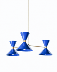 Vivid cobalt and warm brass is the pairing that makes a room feel bold, sunny, and a little Mediterranean, and this mid-century modern Clancy chandelier brings them together beautifully. Three glossy Mediterranean blue double-cone shades radiate from a brass central hub on slim brass arms, in a fun, sculptural MCM silhouette that throws light up and down from each arm. The brass stem and collars warm up the saturated blue and give the whole piece a polished, collected feel. It's built to be the star over a 