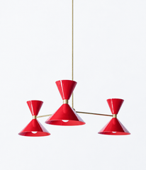Bright red and warm brass is the pairing that makes a room feel bold, confident, and full of energy, and this mid-century modern Clancy chandelier brings them together beautifully. Three glossy red double-cone shades radiate from a brass central hub on slim brass arms, in a fun, sculptural MCM silhouette that throws light up and down from each arm. The brass stem and collars warm up the punchy red and give the whole piece a polished, collected feel. It's built to be the star over a dining table, kitchen isl