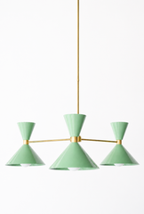 Soft sage green and warm brass is the pairing that makes a room feel fresh, calm, and quietly sophisticated, and this mid-century modern Clancy chandelier brings them together beautifully. Three glossy vista green double-cone shades radiate from a brass central hub on slim brass arms, in a fun, sculptural MCM silhouette that throws light up and down from each arm. The brass stem and collars warm up the gentle green and give the whole piece a polished, collected feel. It's built to be the star over a dining 