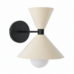 A warm cream wall sconce with black hardware, softer than a stark black-and-white but every bit as graphic, made for a powder room, hallway, or bedside. The Clancy Sconce carries the same sculptural double-cone shade as the Clancy chandelier, a wide cone below and a smaller cone flaring up above, here in glossy cream with a matching black collar, arm, and round backplate. The creamy neutral warms up the crisp black lines, easy against white trim, natural wood, patterned tile, or a moody wall. A versatile pi