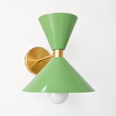 A juicy green wall sconce that makes a powder room, hallway, or bedside feel thought-through. The Clancy Sconce shares its shape with the Clancy chandelier: a broad cone below that pushes a warm glow down over the sink or nightstand, a smaller cone flaring up above, and a raw brass collar cinching the two, all on a round brass backplate. Vista green splits the difference between vintage and garden-room fresh, gorgeous with white subway tile, floral wallpaper, warm oak, or a moodier green wall for a tonal lo
