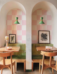 Vista Green Clancy sconces with brass hardware add character to a cozy café nook. Mounted above green velvet booths framed by pink-and-white checkered alcoves, these midcentury modern wall lights from Sazerac Stitches bring stylish, customizable color and designer lighting to hospitality or residential spaces.