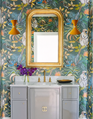 Pair of bold midcentury-inspired Clancy wall sconces with sleek brass accents flanking a tall gold mirror in a playful powder room. The jungle animal wallpaper, marble countertop, and gray vanity create a vibrant, designer look—these customizable Sazerac Stitches sconces add a pop of personality and high-end lighting to eclectic bathrooms or small spaces.