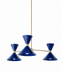 A rich navy chandelier that works as hard as it looks good, made for a dining room, entryway, or bedroom that wants color you won't tire of. The Clancy Chandelier has three arms, each ending in an oversized double-cone shade: a wide cone below that throws light down and a smaller upturned cone above, joined at a raw brass collar. The arms sit at staggered heights off a central brass hub for a relaxed, asymmetric look, and the drop stem can be customized to your ceiling. This deep cobalt-navy is classic and 