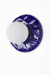 Cobalt blue ceramic wall sconce with frosted globe shade, Leafy Sconce product photo on white background, sculptural leaf relief backplate, modern statement lighting.