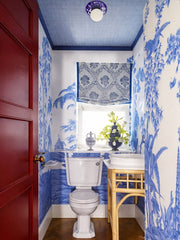 Cobalt blue Lierre ceramic ceiling light with leafy relief texture and frosted globe, installed in a bold blue and white chinoiserie powder room with scenic toile wallpaper, blue grasscloth ceiling, red painted door, bamboo vanity, and patterned Roman shade, statement small bathroom ceiling fixture with color drenched traditional coastal grandmillennial design style, handmade lighting designed and assembled in New Orleans with ceramic made in North Carolina