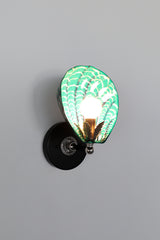 Hand-painted Coquille Sconce glowing with mermaid green ceramic shell, accented by layered white and navy brushstrokes; features black wall plate and silver-toned hardware with leaf detail, one-of-a-kind Art Deco wall light