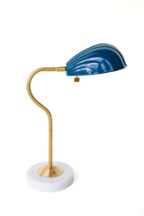 Coquille desk lamp in Lagoon blue with a vintage-inspired brass arm and marble base, featuring an Art Deco shell-shaped shade. This elegant yet vibrant lamp adds a pop of coastal charm and midcentury modern style to desks, bedside tables, or reading corners, perfect for eclectic and minimalist interiors alike