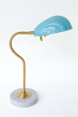 Coquille desk lamp in pastel sky blue with an elegant brass curved arm and a sturdy marble base, featuring a scalloped, Art Deco-inspired shell shade. This versatile midcentury modern lamp brings subtle sophistication and a touch of coastal charm to desks, bedside tables, or reading nooks, ideal for both minimalist and eclectic decor styles.