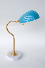 Coquille desk lamp in vibrant teal with a brass curved arm and solid marble base, featuring an Art Deco-inspired shell shade. This stylish midcentury modern lamp adds a coastal vibe and pop of color to any desk, bedside table, or reading nook, perfect for eclectic and contemporary decor styles.