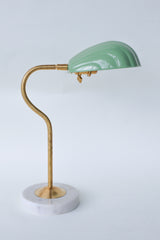 Coquille desk lamp in pastel and muted green with a brass curved arm and solid marble base, featuring an Art Deco-inspired shell shade. This stylish midcentury modern lamp adds a coastal vibe and pop of color to any desk, bedside table, or reading nook, perfect for eclectic and contemporary decor styles.