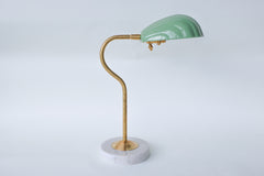 Coquille desk lamp in pastel and muted green with a brass curved arm and solid marble base, featuring an Art Deco-inspired shell shade. This stylish midcentury modern lamp adds a coastal vibe and pop of color to any desk, bedside table, or reading nook, perfect for eclectic and contemporary decor styles.