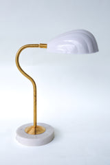 Coquille desk lamp in classic white with an elegant brass curved arm and a sturdy marble base, featuring a scalloped, Art Deco-inspired shell shade. This versatile midcentury modern lamp brings subtle sophistication and a touch of coastal charm to desks, bedside tables, or reading nooks, ideal for both minimalist and eclectic decor styles.