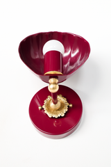 Looking down into the Coquille Sconce, the fluted shell interior catches the light in glossy black cherry powder coat. A cast brass rosette with scalloped edges anchors the color-matched arm, finished with a brass ball and tiny brass thumbscrews on the round backplate. Details like these are why vintage-inspired lighting works in grandmillennial bathrooms, colorful powder rooms, and collected traditional bedrooms.