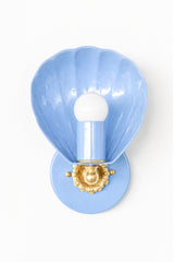 Pastel soft blue lighting sconce in the shape of a shell with cast brass details. Slightly nautical and slightly chinoiserie, this is a delicate looking sconce with beautiful details. It can be used in a bathroom, in a commercial setting, or as an accent piece to provide ambient lighting. We light the coastal vibes.