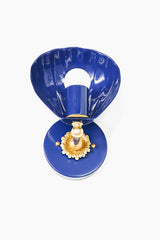 Straight-on studio image of the Navy Coquille Sconce with a glossy blue shell shade, matching round backplate, warm brass accents, and white globe bulb. The scalloped shade gives the fixture a soft, curved shape that feels coastal, feminine, vintage, and a little Art Deco. This blue wall sconce is a strong fit for bathroom lighting, powder room sconces, nautical decor, grandmillennial interiors, beach house lighting, kids bathrooms, guest baths, and colorful bedside lighting.