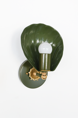 From this angle, the Coquille Sconce shows how the fluting wraps the outer shell like a real scallop. The deep olive powder coat covers shade, arm, and backplate in one mossy, glossy sweep, while the cast brass rosette and ball detail catch the light below the exposed globe bulb. Earthy, sculptural lighting for English cottage bathrooms, moody powder rooms, and collected traditional homes drawn to green with depth.