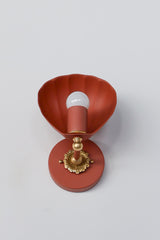 Studio product photo of the Terra Cotta Coquille Sconce shown against a clean light gray background. This sculptural wall sconce features a shell-inspired scalloped shade in a warm terra cotta finish, paired with decorative brass detailing and a round matching backplate. The exposed globe bulb highlights the fixture’s playful yet elegant silhouette, making it a strong option for coastal lighting, feminine interiors, powder rooms, bedside wall lighting, and statement bathroom sconces.