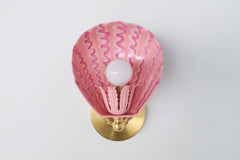 Detail view of blush and raspberry hand-painted Coquille sconce with golden brass gooseneck arm, shell-shaped powder-coated steel shade, and scalloped brass backplate – one-of-a-kind wall light for colorful eclectic homes, kid-friendly spaces, and whimsical decor lovers