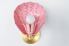 Front-facing view of the Coquille wall sconce in blush pink with raspberry squiggle pattern, hand-painted on powder-coated steel, featuring a fluted socket cup and solid brass hardware – whimsical pink shell light perfect for maximalist bathrooms, coastal-inspired kids’ rooms, or eclectic gallery walls