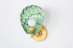 Side angle of the one-of-a-kind Coquille wall sconce with a scalloped shell design hand-painted in shades of green, including vista green accents on powder-coated steel, mounted with a vintage-style brass backplate and socket, perfect for maximalist or Art Deco wall lighting in bathrooms, hallways, or powder rooms