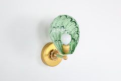 Side angle of the one-of-a-kind Coquille wall sconce with a scalloped shell design hand-painted in shades of green, including vista green accents on powder-coated steel, mounted with a vintage-style brass backplate and socket, perfect for maximalist or Art Deco wall lighting in bathrooms, hallways, or powder rooms