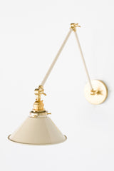 Cream and Brass adjustable cone sconce for kitchen lighting above windows or above open shelving cabinetry.  Also makes a great bedside reading light that frees up space on your nightstands. Comes in three finishes and over 30 colors for a custom look.  Available in neutrals or fun, bright colors that work in any maximalist or kid-friendly space.  Classic style wall sconce that has been updated by our curated color palette of brights, darks, and pastel hues.  Designed and made by Sazerac Stitches.