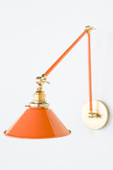 Bright Orange and Brass adjustable cone sconce for kitchen lighting above windows or above open shelving cabinetry.  Also makes a great bedside reading light that frees up space on your nightstands. Comes in three finishes and over 30 colors for a custom look.  Available in neutrals or fun, bright colors that work in any maximalist or kid-friendly space.  Classic style wall sconce that has been updated by our curated color palette of brights, darks, and pastel hues.  Designed and made by Sazerac Stitches.