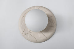 Studio photo of Lierre ceramic wall sconce in unglazed cream porcelain, raised leaf relief plate with matte white globe, sculptural lighting for organic modern and grand millennial interiors.
