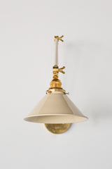 Cream and Brass adjustable cone sconce for kitchen lighting above windows or above open shelving cabinetry.  Also makes a great bedside reading light that frees up space on your nightstands. Comes in three finishes and over 30 colors for a custom look.  Available in neutrals or fun, bright colors that work in any maximalist or kid-friendly space.  Classic style wall sconce that has been updated by our curated color palette of brights, darks, and pastel hues.  Designed and made by Sazerac Stitches.