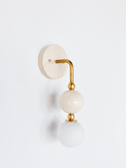 A cream and brass wall sconce built for traditional bathroom vanity lighting, powder room sconces, or nursery lighting searches. The sculptural stacked-orb shape gives a neutral colorway real presence instead of reading flat or builder-grade. Good for interior designer resource lighting projects, custom lighting for interior designers, or anyone layering a neutral fixture into a room that's already doing the color work elsewhere.