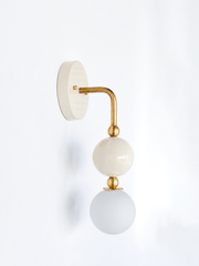 Searching for powder room sconces or a nursery chandelier alternative that isn't stark white? This cream and brass wall sconce works for traditional bathroom vanity lighting, transitional powder rooms, or a soft neutral base in an otherwise colorful room. Cream glass orb with brass ball accents and an exposed frosted globe bulb. Made-to-order, American made lighting for interior designers building out a traditional or grandmillennial-adjacent space that needs one quiet, well-proportioned fixture.