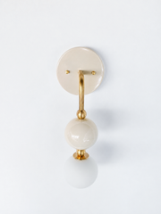 A closer look at the cream and brass Ida sconce, showing the brass ball accents and glass orb against the matching cream backplate. Works for traditional bathroom vanity lighting, powder room sconces, or a nursery chandelier alternative, especially in a room where the wallpaper or tile is already doing the color work and the fixture needs to stay quiet. American made, made-to-order lighting.