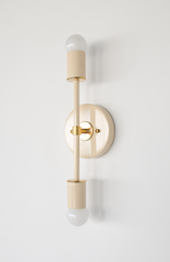 Monochromatic cream and brass Medium Thalia Sconce with double globe bulbs, a color-drenched mid century modern wall sconce with sleek vertical silhouette and round backplate, modern minimalist bathroom vanity light or bedside wall lamp by Sazerac Stitches