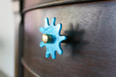 tiffany blue pearl splat knob with brass details on a dark wood nightstand
