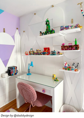 Colorful teenage girls bedroom with a white desk featuring pink daisy drawer pulls, a pink boucle desk chair, white geometric wall paneling, floating shelves with toys and decor, and playful pastel accents. Feminine kids room design with flower drawer knobs, girly desk ideas, cute tween bedroom furniture, colorful girls room decor, whimsical bedroom styling, and fun statement hardware for a custom desk.