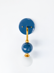 Searching for a blue bathroom sconce, coastal bathroom lighting, or Southern traditional vanity fixture? This denim blue and brass sconce brings a deeper navy-adjacent blue to a sculptural single-arm design. Glossy denim glass orb, brass ball detailing, and a frosted globe bulb. Made-to-order, American made lighting suited to coastal traditional, Southern feminine, or Chinoiserie-leaning bathrooms and powder rooms.