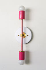 Colorblocked Thalia sconce in doll pink, blush pink, and white with brass accents, modern two-light bathroom vanity wall sconce for kids bathroom or feminine powder room