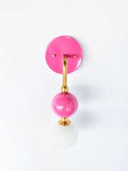 A bright doll-pink wall sconce for anyone building a bathroom, powder room, or girl's bedroom with real personality. The Ida sconce stacks a glossy pink powder-coated sphere over a frosted glass globe, joined by warm brass hardware and a round pink backplate. Candy-colored and playful without tipping into childish, it's a happy pick for colorful, grandmillennial, or maximalist spaces that skip the safe answer.