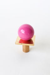 Close-up of the Square Gumball Drawer Pull in glossy Doll Pink and brushed brass, featuring a bold pink powder-coated steel ball atop a square brass plate. Modern cabinet knob, ideal for midcentury furniture, kids’ room dressers, or colorful kitchen cabinet hardware. Handmade in the USA.