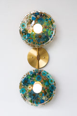 Modern two light wall sconce with brass hardware. Features resin-encapsulated greenery, ferns, and leaves.  Adds a real-like nature theme to any interior design project.  Called the Botanico Sconce by Sazerac Stitches. Features blue & white flowers with white greenery