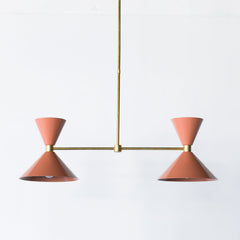 Two Light Linear Chandelier in peach and brass.  Midcentury modern style cone shape.  Perfect over long dining tables, a kitchen island, and narrow spaces.  Adds a pop of peach fuzz Pantone color of the year to any decor style.